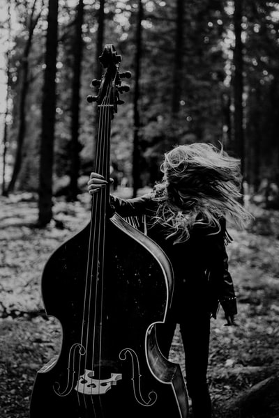 女人黑色长袖连衣裙弹吉他在灰度摄影
